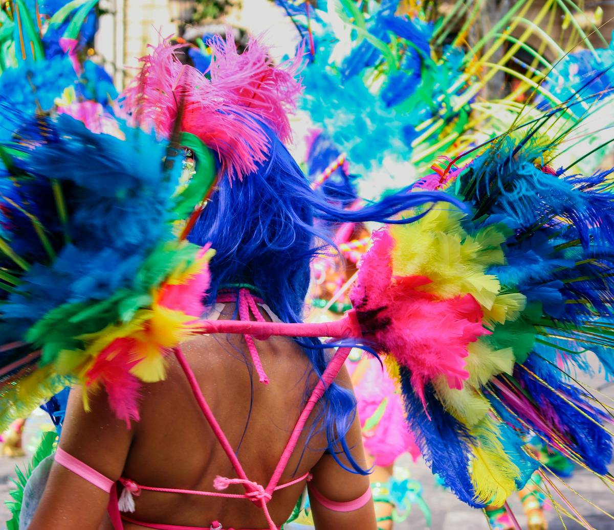 colorful carnival headpiece designs featuring feathers, beads, and floral accents on a mannequin head